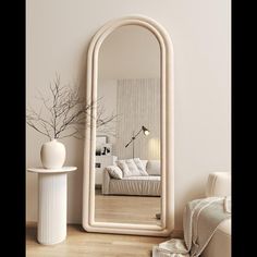 a mirror sitting on top of a wooden floor next to a white vase and lamp