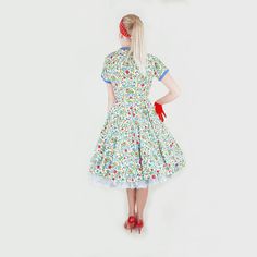 "This beautiful dress is summer-ready, made of unlined cotton piqué in white, with a blue, green, red, and yellow flower print. Blue piqué edges the neckline and sleeve cuffs. The dress has small blue-covered buttons all the way down the front. With a fitted bodice, the skirt is a full circle, flaring smoothly in back and with four front pleats. Short kimono sleeves; narrow matching belt. The label is from a shop, Bernard's Spokane. Please note: I show the dress with a crinoline beneath, to acce Fitted Cotton Floral Sundress, Multicolor Cotton Floral Dress With Short Sleeves, Short Sleeve Cotton Floral Dress For Garden Party, Cotton Floral Dress Short Sleeve For Garden Party, Cotton Floral Dress With Short Sleeves For Garden Party, Cotton Full Skirt Summer Dress, Fitted Multicolor Floral Cotton Dress, Fitted Multicolor Cotton Floral Dress, Retro Cotton Dress For Garden Party