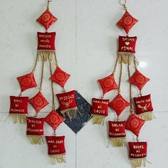 red and gold ornaments hanging from the side of a white tile wall with words written on them