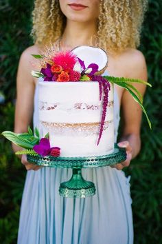 a woman holding a cake with flowers on it