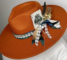 "Lainey Wilson inspired custom made wide-brim hats.  Measures 22\" but has adjustable straps inside.  This one is a burnt orange felt, with a silk wild rag, lace & leather hat band. It also features feathers wild flowers & a burnt playing card.  I have a variety of other custom made hats in stock & can custom make anything to your liking!  These are perfect for Christmas gifts for any concert, rodeo or other event!" Bohemian Fedora For Western-themed Winter Events, Bohemian Brown Hat With Feather Trim, Bohemian Brown Hats With Feather Trim, Brown Feather Trim Hat For Fall, Bohemian Fedora With Feather Trim, Bohemian Fedora Felt Hat With Feather Trim, Bohemian Felt Fedora With Feather Trim, Bohemian Fedora With Feathers For Fall, Cowboy Hat Crafts