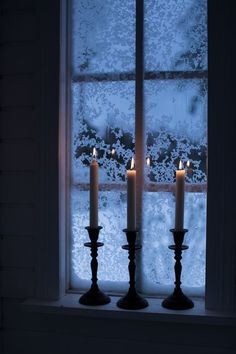 three candles are lit in front of a window