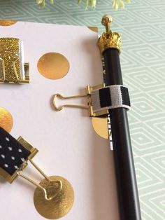 a notepad with gold and black decorations on it, next to a fountain pen