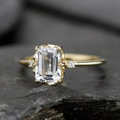 an emerald cut diamond ring on top of a rock