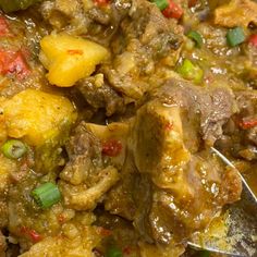 a close up of food with meat and vegetables on a plate next to a spoon