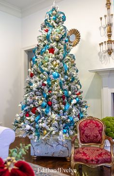 a white christmas tree with red, blue and gold ornaments in a living room setting