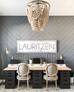 an office with two desks, chairs and a chandelier