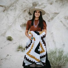 a woman is holding a blanket in the desert