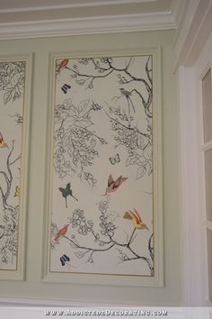 two framed pictures on the wall with birds and flowers in them, hanging above a window