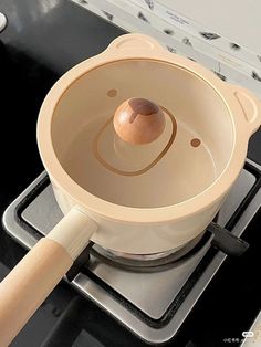 a wooden handle is on the top of a stove burner with an egg in it