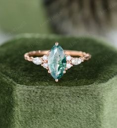 a green and white stone ring sitting on top of a green cloth