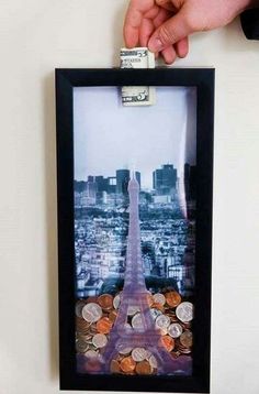 a person is holding up a picture frame with money in front of the eiffel tower