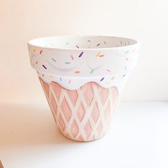 a pink and white cup with sprinkles on it