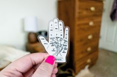 a person holding up a fake hand with writing on it in front of a bed