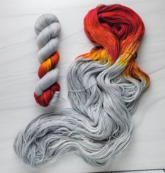 two skeins of yarn next to an orange and gray leaf on a white surface