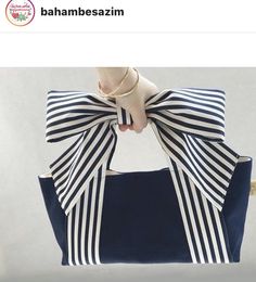 a woman holding a blue and white bag with a bow on it's handle