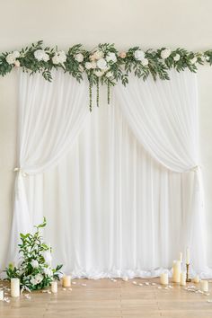 a wedding ceremony with white flowers and greenery on the drapes over the windows