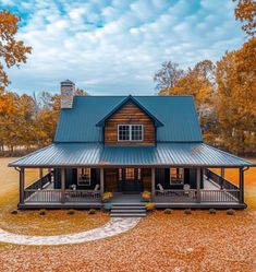 a house with a metal roof in the middle of an open field surrounded by trees