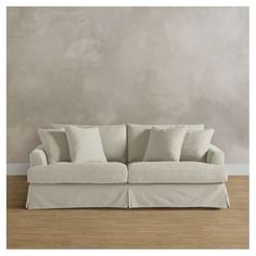 a white couch sitting on top of a hard wood floor next to a gray wall