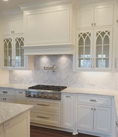 a kitchen with white cabinets and marble counter tops