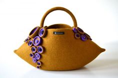 an orange purse with purple flowers on the front and bottom, sitting on a white surface