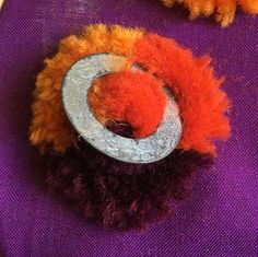 two orange and purple pom poms sitting on top of a purple table cloth