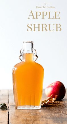 an apple shrub in a glass bottle on a wooden table with apples and leaves around it