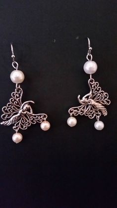 Silvery fantasy-themed fairy charm earrings with white glass-pearl beads. Silver Fairycore Earrings For Party, Silver Fairy Grunge Dangle Jewelry, Fairy Grunge Silver Dangle Jewelry, White Fairycore Jewelry For Party, Whimsical Handmade Pearl Jewelry, Whimsical White Pearl Jewelry, Silver Fairy Earrings For Party, Nickel-free Fairycore Earrings For Jewelry Making, Silver Fairy Style Party Earrings