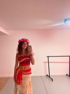 a woman in a belly dance outfit taking a photo with her cell phone while standing on the floor