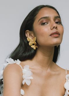 a woman wearing large gold earrings with flowers on the back of her head and shoulder