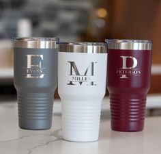 three different colored tumblers sitting on top of a counter