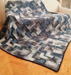 a white couch sitting next to a wooden floor covered in a blue and gray blanket