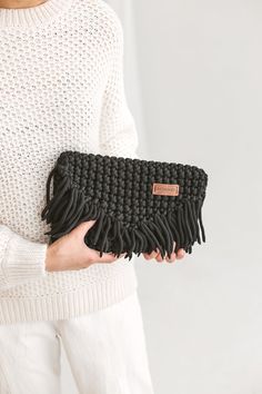 a woman is holding a black clutch bag