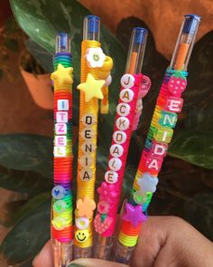 three pens with different colored writing on them in front of a potted green plant