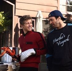 two men standing next to each other holding lobsters