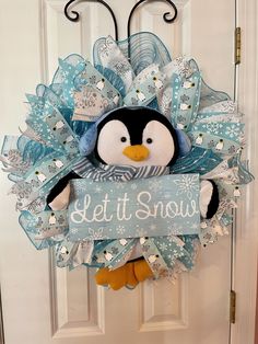 a penguin is hanging on the front door with a let it snow sign attached to it