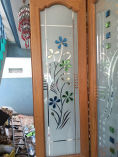 two glass doors with flowers on them in front of a building under construction, one has been painted and the other is stained