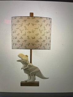 a lamp that is on top of a wooden base and has a dinosaur design on it