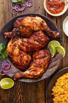 chicken and rice on a wooden table with limes, cilantro sauce and red onion