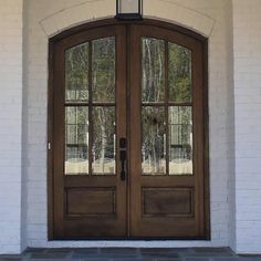 the front door to a white brick building with two double doors and glass panels on each side