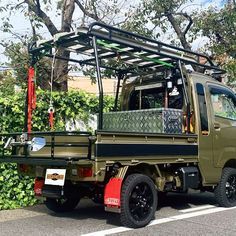 an army green truck parked on the side of the road next to bushes and trees