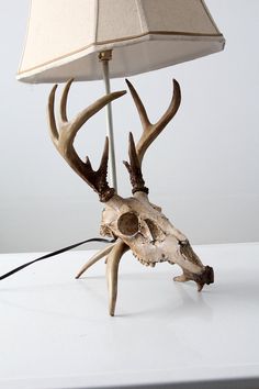 a lamp that is on top of a table with a deer's head attached to it