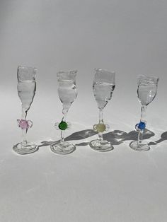 five wine glasses are lined up on a white surface with one empty glass in the middle