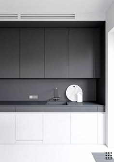 a modern kitchen with white cabinets and gray counter tops, along with a sink in the center