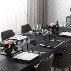 a dining table set with place settings and flowers