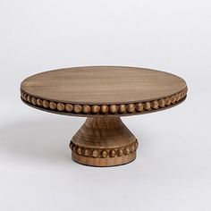 a round wooden table with beading on the top and bottom, against a white background