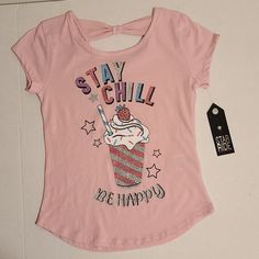 Cute Girls Top Features Short Sleeves, A Stay Chill Glittery Graphic Design, And A Bow On Upper Back. 60% Cotton And 40% Polyester. Machine Wash. Cute Glitter Print Short Sleeve Tops, Cute Short Sleeve Tops With Glitter Print, Casual Pink T-shirt With Glitter Print, Casual Glitter Print T-shirt For Spring, Casual T-shirt With Glitter Print, Casual Cotton Tops With Glitter Print, Casual Glitter Print Tops For Spring, Pink Casual Top With Glitter Print, Pink Glitter Print Tops For Spring