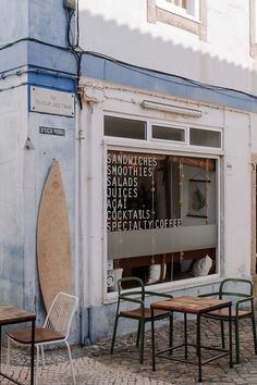 there are some tables and chairs outside the storefront window that says sandpipes, smoothies, salads, satays, cocktails, coffee