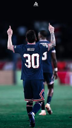 two soccer players are walking on the field with their arms in the air and one is holding his hands up