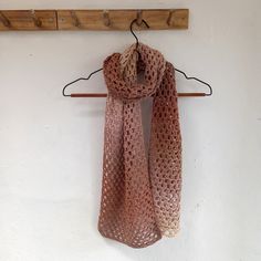 a crocheted scarf hanging on a coat rack next to a coat hanger